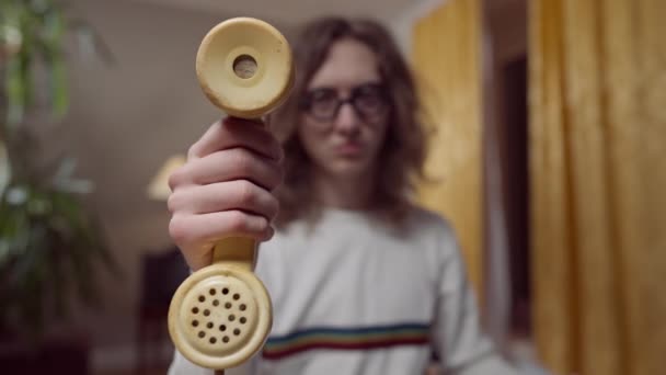 Close-up de telefone amarelo vintage aparelho na mão masculina com enevoado 1980 1990 nerd no fundo. Jovem caucasiano segurando retro desatualizado telefone antiquado posando dentro de casa. — Vídeo de Stock