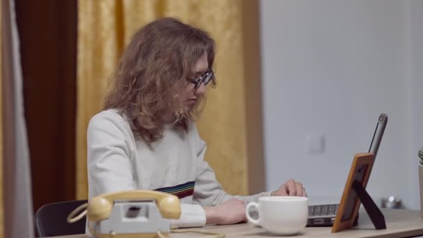 ヴィンテージノートパソコンのキーボードとあくびを入力して疲れ80年代のオタクの側面図。屋内で自宅で若い白人男性のコーディングプログラミングやサーフィンインターネットを着用。レトロテクノロジーのコンセプト. — ストック動画