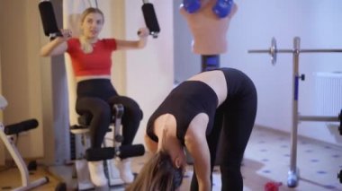 Kamera, arka planda egzersiz makinesi kullanarak kasları çalıştıran, bulanık Kafkas dostu olarak öne eğilen genç, zayıf, kendine güvenen sporcunun hareketlerini takip ediyor. Spor yaşam tarzı konsepti.