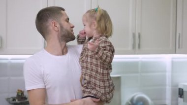 Küçük kızını öpen, kameraya bakıp gülümseyen mutlu beyaz bir baba resmi. Neşeli yakışıklı bir adamın portresi. Evde bir çocukla eğleniyor. Yaşam tarzı ve ebeveynlik.