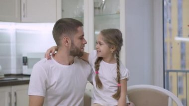 Neşeli, güzel küçük kız ve mutlu genç adam hafta sonu evde öpüşüp gülüyor. Neşeli beyaz baba-kız portresi. Kapalı alanda eğleniyorlar..