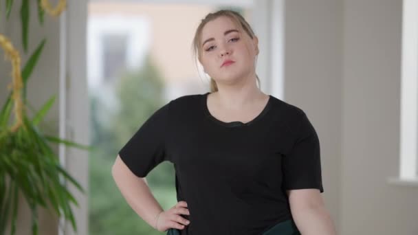 Plano medio de joven encantadora mujer regordeta haciendo ejercicio con mancuerna en casa y bostezando. Retrato de la somnolienta atleta caucásica de talla grande entrenando en el interior de la mañana. Deporte y fitness. — Vídeo de stock