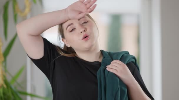 Portrait of tired overweight sportswoman wiping forehead with hand and smiling looking at camera. Positive charming exhausted Caucasian woman posing after morning workout at home. — Stock Video