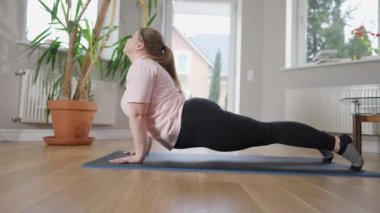 Yılan pozu vermiş esnek, iri yarı, beyaz kadın figürleri. Evde çalışan yoğun beyaz yogillerden oluşan geniş açılı bir çekim. Yoga ve spor konsepti.