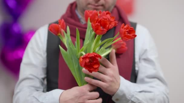 Buquê de tulipas vermelhas em mãos caucasianas masculinas. Casal adulto amoroso irreconhecível ou namorado cheirando belo presente para o dia dos namorados para a esposa ou namorada. Romance e amor conceito. — Vídeo de Stock