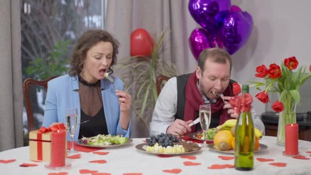 Homme caucasien en colère debout de la table à manger Valentines et laissant la femme seule devant la caméra. Couple adulte discuté sur des vacances romantiques à la maison à l'intérieur. Mariage et difficultés relationnelles. — Video