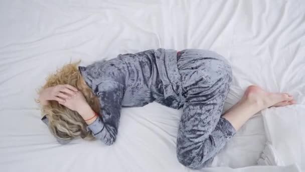 Κάτοψη της νεαρής καταθλιπτικής απογοητευμένης γυναίκας που κλαίει ξαπλωμένη στο κρεβάτι στο σπίτι. Απελπισμένα μοναχικά, αδύναμα ξανθά χιλιετίες με πιτζάμες στην κρεβατοκάμαρα το πρωί. Κατάθλιψη. — Αρχείο Βίντεο