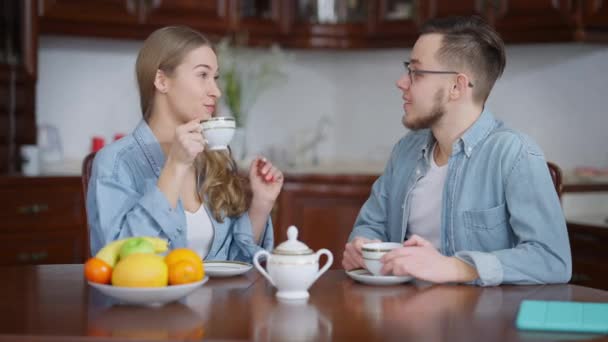 Orta boy mutlu, beyaz bir çift sabah kahvesini yudumlarken gülümsüyor. Neşeli bir milenyum erkeği ve kadını evde hafta sonunun tadını çıkarıyor.. — Stok video