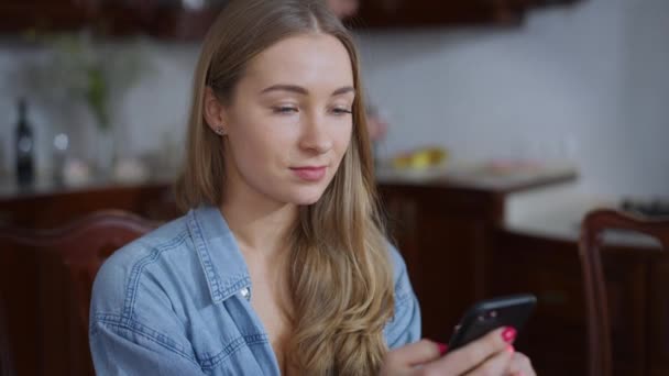 Joven absorbido millennial mujer mensajes de texto en el teléfono inteligente como hombre cariñoso abrazar y besar a la pareja. Feliz pareja caucásica disfrutando de la mañana en casa dentro. Concepto de amor y unidad. — Vídeos de Stock