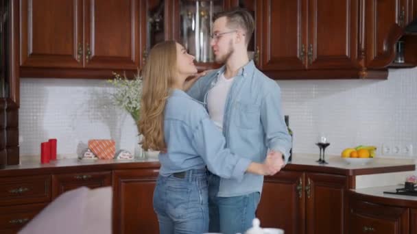 浪漫的爱千禧夫妇在家里的厨房里跳舞。深情的白人青年男女在室内慢舞。浪漫与结合的概念. — 图库视频影像