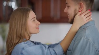 Sevgili milenyum çiftimizin hafta sonu kapalı mekanda öpüşürken burunlarını sürtmelerinin yan görüntüsü. Kafkasyalı kadın ve erkeği mutlu bir şekilde evlerinde vakit geçiriyorlar. Aşk konsepti.