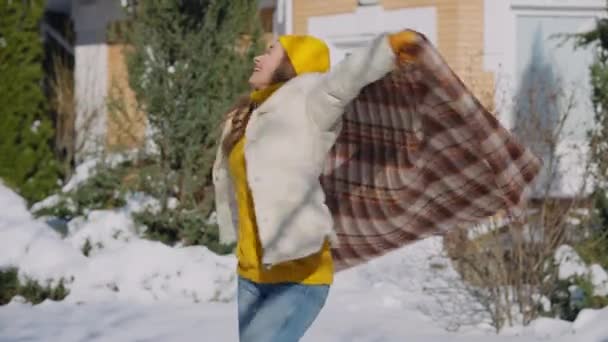 Portret van een vrolijke vrolijke vrouw die een deken vasthoudt op een zonnige winterdag buiten. Vreugdevolle zorgeloze blanke millennial plezier hebben op besneeuwde achtertuin poseren kijken naar camera. — Stockvideo