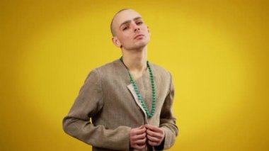 Erkek eşcinsel düğmeli kadın ceketinin kameraya bakarken orta boy görüntüsü. Sarı arka planda poz veren beyaz kadın portresi. LGBTQI ve cinsiyet kimlik kavramı.