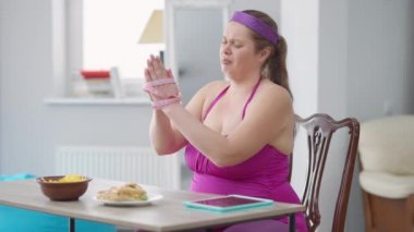 Elleri bant ile sarılı, ağlayan, ağzı kameraya bakarak sağlıksız cips yiyen depresif obez kadın portresi. Evde hayal kırıklığına uğramış şişman Kafkasya milenyum diyeti..