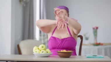 Şişman, genç, beyaz bir kadın ellerinde fiş yiyerek şerit çekmekten kurtuluyor kameraya bakarak güçlü bir jest yapıyor. Obezite ve diyet kırma kavramı.