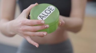 Yakın plan ince kadın elleri Aloe kremini açıyor. Tanımlanamayan Kafkas milenyumu içeride gençleştirme nemlendiricisi gösteriyor. Vücut bakımı ve kadınlık kavramı.