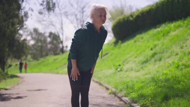 Amplio tiro de mujer mayor de pelo gris hermosa ajuste flexión en el entrenamiento en cámara lenta al aire libre a la luz del sol. Retrato de deportista caucásica activa confiada haciendo ejercicio en el parque de verano. — Vídeos de Stock