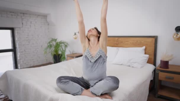 Joven embarazada hermosa mujer estirándose sentada en la cama por la mañana. Retrato de relajado encantador expectante caucásico en pijama despertando en el dormitorio en casa. Embarazo y estilo de vida. — Vídeos de Stock