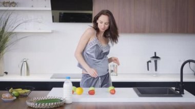 Mutfakta ağır çekimde dans eden mutlu hamile genç kadın. Evde eğlenen pozitif, neşeli esmer, beyaz bir kadının portresi. Hamilelik ve mutluluk kavramı.