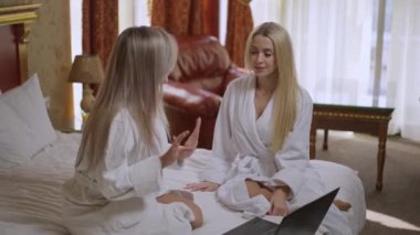 Gülümseyen, genç ve güzel bir kadın otel odasında dizüstü bilgisayarla sosyal medyada yavaşça sörf yapıyor. Güzel, beyaz, güzel bayanların dedikodusu. Kadınlık ve söylenti kavramı.