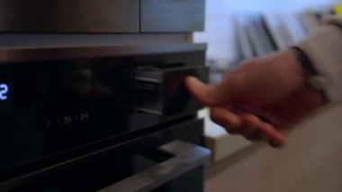 Yakın plan beyaz erkek eli modern yeni fırının buhar buharlaştırma bölümünü kapatıyor. Pahalı dükkanda lüks siyah ev aletleri gösteren tanınmamış bir adam..