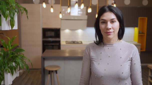 Portrait of confident Caucasian woman posing in furniture store as girl choosing new kitchen at background. Happy mother buying appliances and furnishing with daughter in shop. Slow motion. — Stock Video