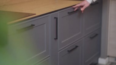 Beyaz bir erkek mutfak dolabının çekmecesini açıp kapatıyor ve içinde ışıklar yanıp sönüyor. Mağazada modern mobilya işlevini gösteren tanınmayan bir erkek satıcı..