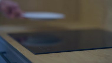 Arka planda beyaz tabaklar koyan erkek eli ile yakın çekim elektrikli soba. Mağazada yeni ev aletlerini dekore eden tanınmamış beyaz bir adam. Konsept satılıyor.
