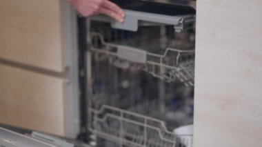 Erkek eli mutfakta ya da evdeki bulaşık makinesinin kapısını kapatıyor. Tanımlanamayan beyaz adam içeride mutfak malzemeleri satmayı seçiyor..