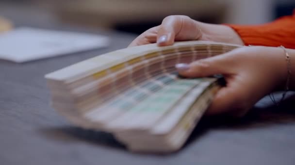 Mani femminili che mostrano una scelta multicolore di campioni di colore all'interno. Irriconoscibile giovane donna caucasica pubblicità varietà di design per mobili in negozio di famiglia. — Video Stock