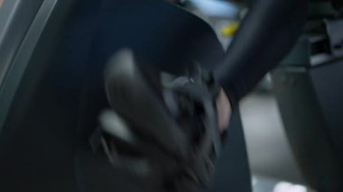 Spor ayakkabılı kadın ayaklar içeride egzersiz bisikleti sürüyor. Spor salonunda ya da evde antrenman yapan, tanınmayan, zayıf, beyaz bir kadın. Spor ve spor konsepti.