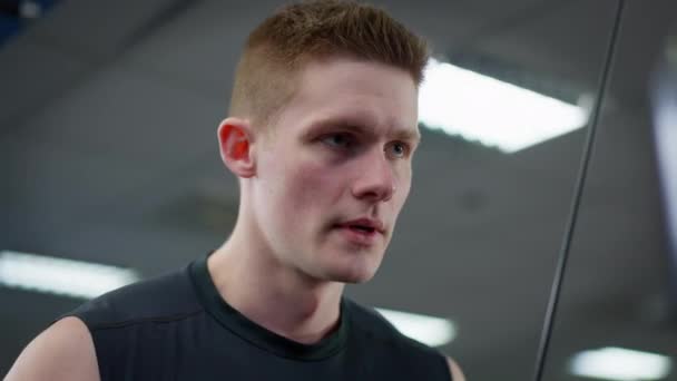 Retrato de primer plano del entrenamiento de deportista guapo concentrado en el gimnasio. Un joven caucásico transpirante haciendo ejercicio en el interior. Concepto de masculinidad y estilo de vida saludable. — Vídeos de Stock