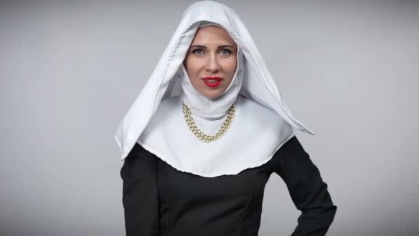 Уверенная в себе веселая женщина в костюме монахини, висящая на высоких каблуках на плечах и уходящая. Портрет позитивной кавказской провокационной стильной дамы, позирующей на сером фоне. — стоковое видео