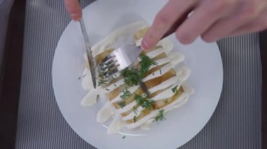 Üst düzey erkek elleri, içi doldurulmuş krep ve yemek tabağı kesiyor. Kafenin içinde lezzetli bir tatlı yiyen, tanınmayan beyaz bir adam..