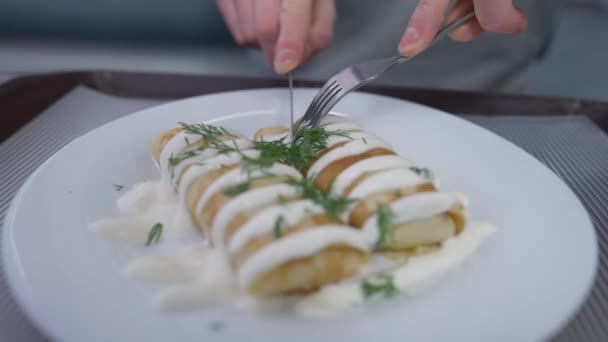 Yakın plan lezzetli bir tatlı, erkek eli çatal ve bıçakla öğle yemeğini kesiyor. Kafeteryada tatlı sarılmış krep tadıyor. Kapalı alanda.. — Stok video