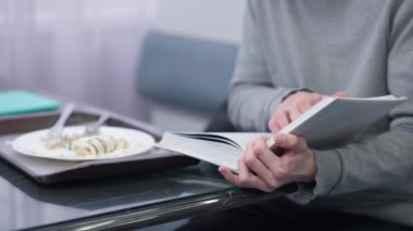 Tanımlanamayan Kafkasyalı genç adam kitap okuyor. Kapalı alandaki kantinde rulo doldurulmuş gözleme yiyor. Masada oturuyor. Erkek zeki dahi öğrenci kafeteryada yemek ve öğrenim görüyor..
