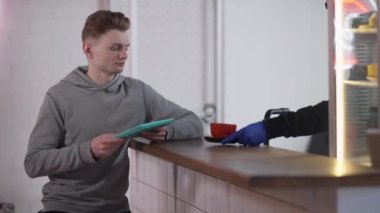 Kantinde internette sörf yapan öğrenci için kahve fincanı veren tanınmamış bir adam. Erkek kahveci, sabahları kafeteryada erkek siparişi veriyor..