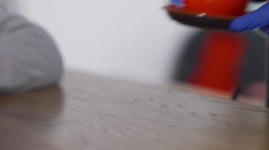 Kafe tezgahındaki müşteriye kırmızı kahve fincanı uzatan tanınmamış barista. Eldiven giymiş erkek eller kafeteryadaki beyaz erkek alıcıya espresso veriyor. Servis kavramı.