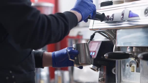 Kahve makinesinde süt içtikten sonra buhar çubuğu temizleyen tanınmamış erkek barista. Kafkasyalı profesyonel bir adam lokanta kafeteryasında lezzetli bir içecek hazırlıyor.. — Stok video