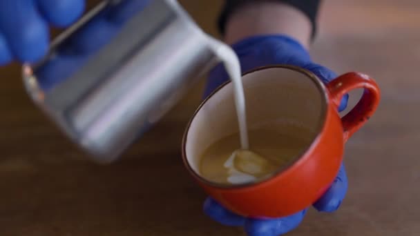 Aus nächster Nähe Milch in Cappuccino gießen und Herzform zeichnen. Unbekannter männlicher Barista bereitet im Restaurant-Café drinnen Heißgetränk zu. Dienstleistungs- und Nahrungsmittelindustrie. — Stockvideo