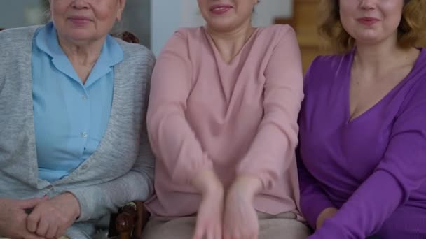 Tres mujeres irreconocibles de diferentes edades abrazándose sonriendo sentadas en un cómodo sofá en casa adentro. Feliz familia multigeneracional disfrutando de la reunión. Concepto de reunión y unidad. — Vídeos de Stock