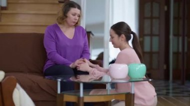 Stresli, beyaz, genç bir kadının, annesinin saçlarını okşarken dizlerinin üstüne çöktüğü bir sahne. Nazik, sevgi dolu bir ebeveynin portresi evde bin yıllık üzüntüyü yatıştırıyor..