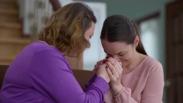 Κλαίγοντας μητέρα και κόρη θρηνώντας κρατώντας το χέρι κάθεται στο σπίτι μέσα. Θλιβερή Καυκάσια όμορφη ενήλικη και νέες γυναίκες που αλληλοϋποστηρίζονται σε δύσκολους καιρούς. Θλίψη και οικογενειακή ενότητα έννοια. — Αρχείο Βίντεο