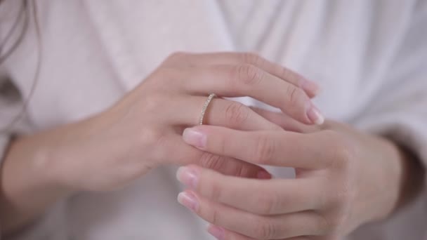 Yakın plan beyaz kadın, genç eller parmağına nişan yüzüğü takıyor. Evde beyaz bornozlu, tanınmayacak kadar mutlu nişanlı bir kadın var. Mutluluk ve evlilik kavramı. — Stok video