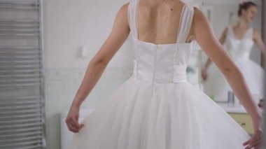 Arka planda aynada bulanık yansıması olan beyaz bir gelinlikle ağır çekimde dönen tanınmaz haldeki mutlu genç gelin. Neşeli, heyecanlı, beyaz, zayıf kadın. Sabahın tadını çıkarıyor..