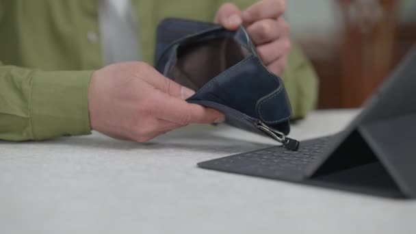 Primer plano manos estresado hombre examinando cartera vacía sentado en la mesa con la tableta. Irreconocible joven caucásico sin trabajo freelancer decepcionado con los ingresos. Concepto de pobreza y estrés. — Vídeos de Stock