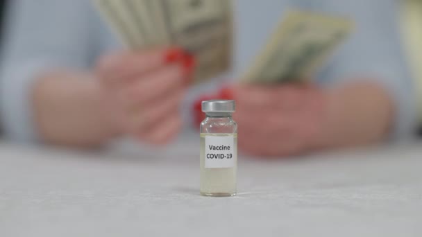 Yakın plan Covid-19 aşısı, yaşlı bir kadının arka planda para sayması. Koronavirüs aşısı sorunu ve yoksul ülkelerde ödeme. Tanınmayan emekli salgında sağlığıyla ilgileniyor.. — Stok video