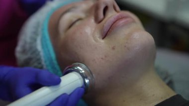 Estetisyen, modern güzellik salonundaki bir müşteri için donanım kozmetolojisi prosedürü uyguluyor.