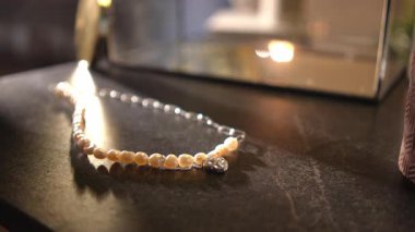 Kadın eli nazikçe siyah, zarif bir taş yüzeyden kalp şeklinde kolyesi olan güzel bir inci kolyeyi kaldırıyor.