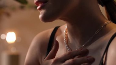 Zarif bir kadının güzel bir inci ve gümüş zincirli kolyeye dokunuşunun yakın çekimi.